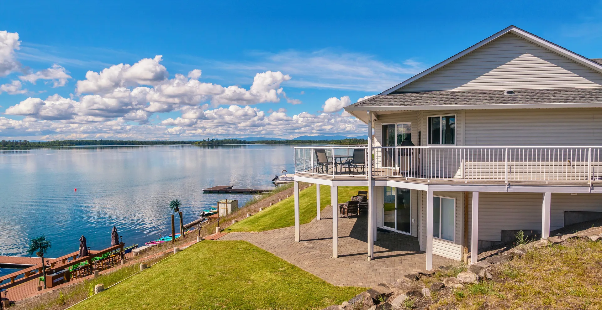 Large two-storey lake house with wraparound deck above a calm bay
