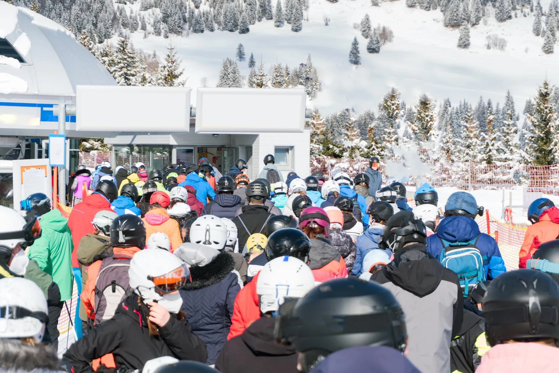 Crowd of skiers in helmets queuing for a chairlift on a busy day