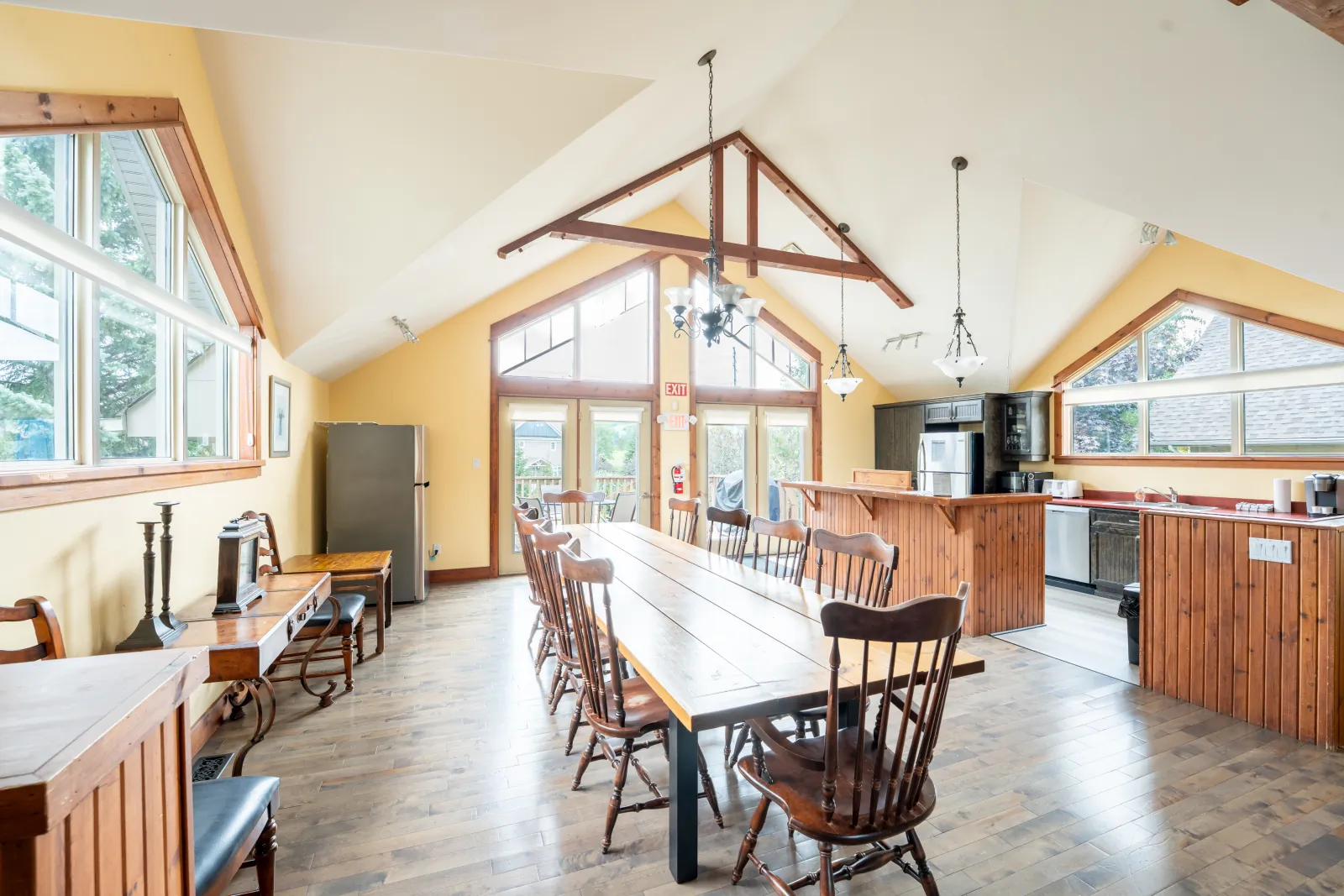 The Aurora gallery: long dining table and kitchen beneath the timber trusses