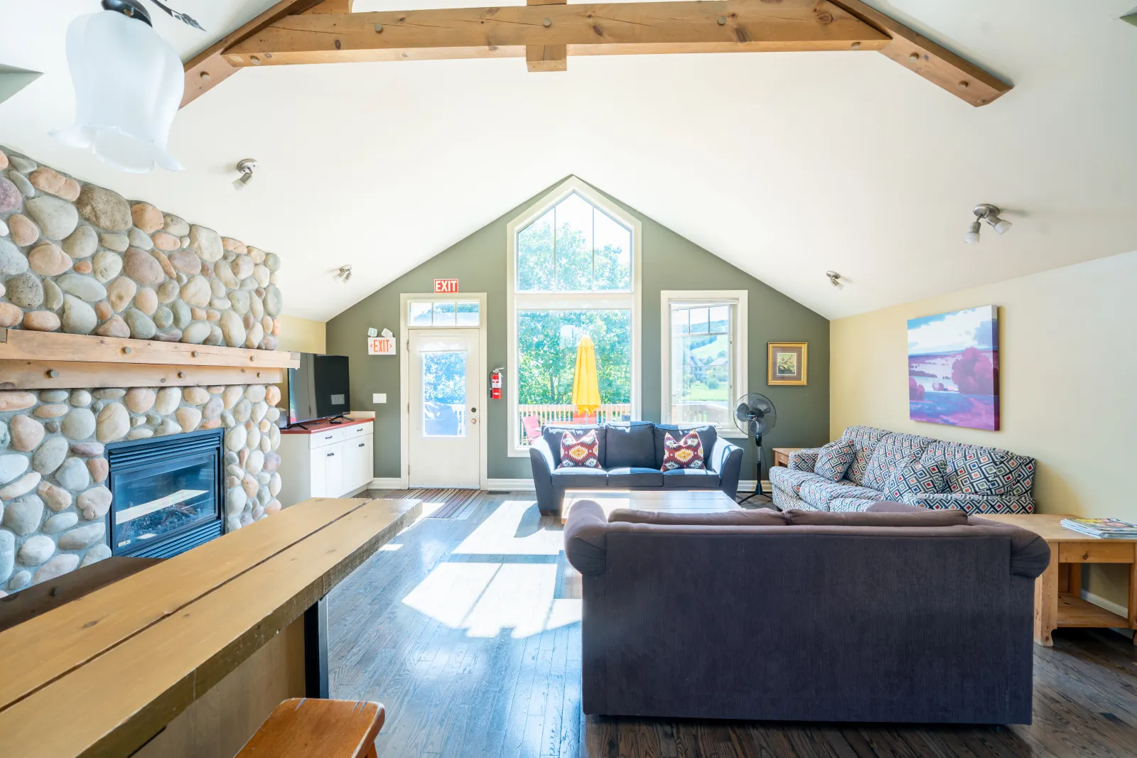 The Corona gallery: sofas beside the stone fireplace under the peaked window