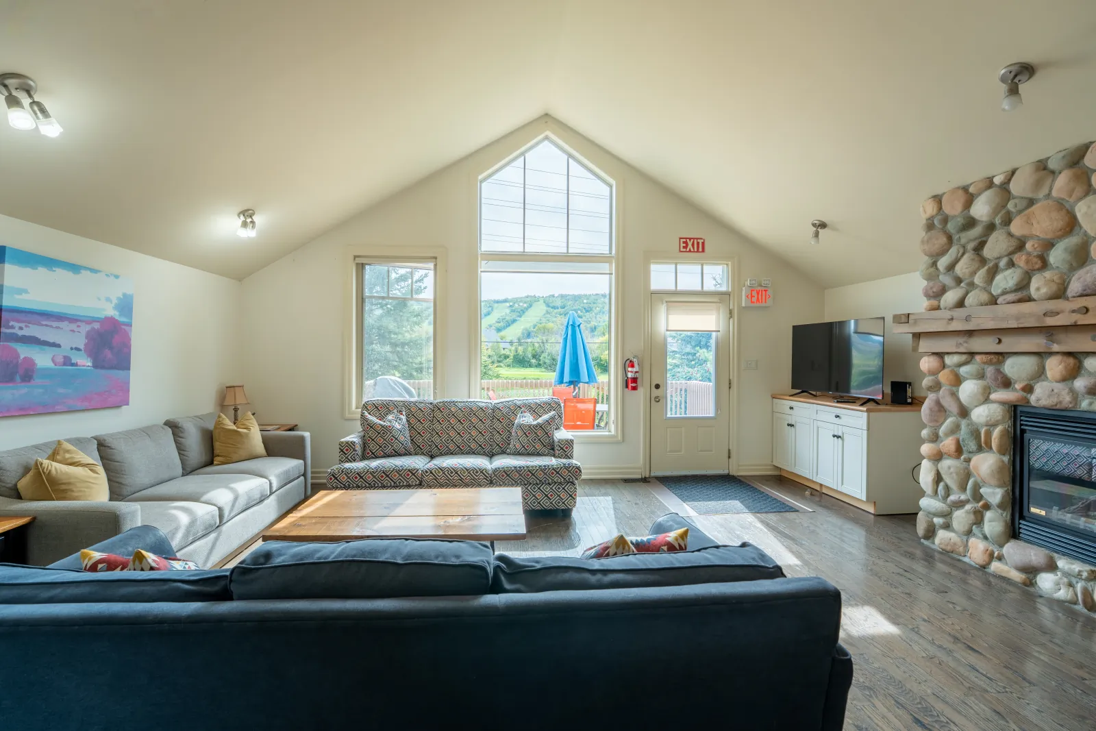 The Prima gallery: sofas and TV beside the stone fireplace
